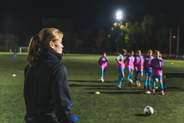 a female coach talking to her football player girls and making them ready for practice. High quality photo