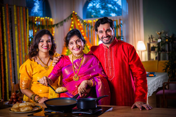 Indian family in traditional wear cooking food for diwali festival celebration at home - group photo