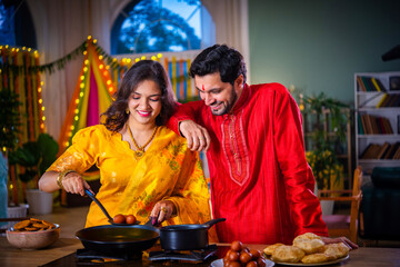 Indian young husband surprises wife with gift while cooking food on diwali festival eve in kitchen