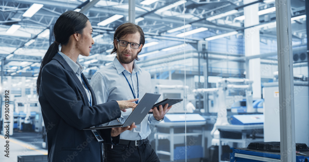 Aufkleber Portrait of a Cheerful Engineer and Happy Asian Scientist Using Laptop and Tablet Computers, Talking in a Factory Facility with Robots Producing Modern Electronic Components for Different Industries