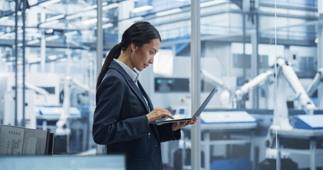 Production Line Technician Working on a Laptop Computer at a Factory Office. Asian Female Software...