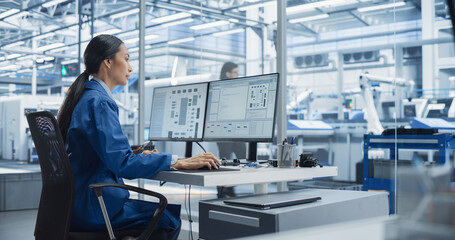 Experienced Female Software Developer Working in Office, Using Desktop Computer and Overlooking Production at a Modern Automated Electronics Manufacture with Robotic Arms. Administrator at Work