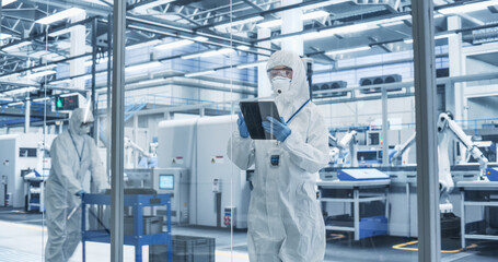 Portrait of a Female Worker Wearing Full-Body Protective Coveralls, Mask and Goggles at a...