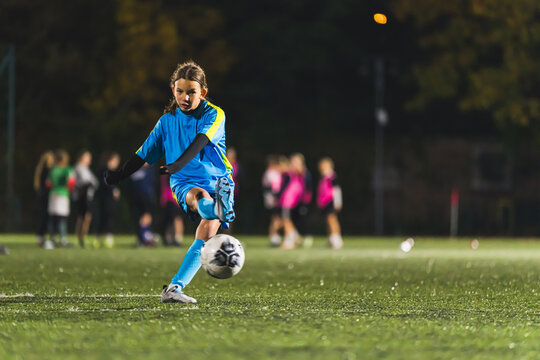 teenage girl soccer player practicing with football ball, Young sportive girl training in blue uniform. High quality photo
