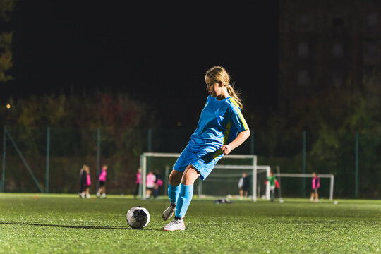 Kids soccer football - young little girl is shooting ball at soccer field. High quality photo