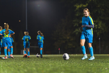 soccer player young girl in light blue uniform playing with a ball at the stadium, full shot. High quality photo