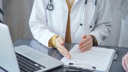 Fototapeta premium Doctor is talking with patient. Close-up of a doctor's hands gesturing above the table in medical office. Medicine and health care concept