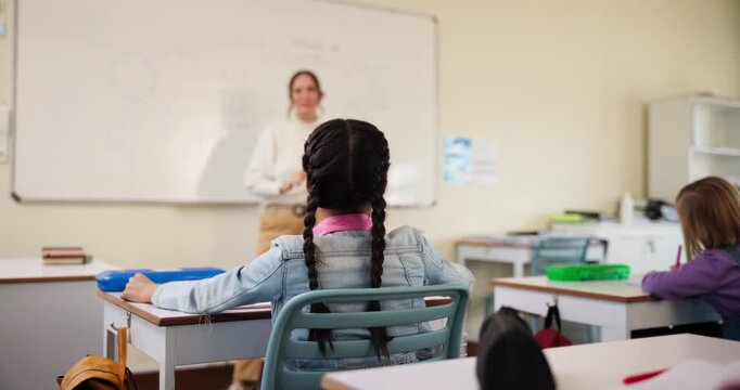 Student, question and hand up in classroom for learning, development and growth as youth with math. Young girl, asking and children in kindergarten or elementary school for knowledge, study and test