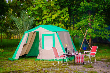 Camping tents at night, vintage cabin tents,  Antique lanterns, retro chairs, and outdoor coffee-making facilities on wooden tables in a forest
