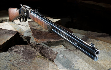Lever action rifle on  stone with a dark background