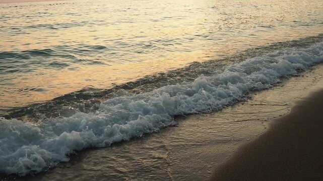 Waves gently lap at shore during stunning sunset over ocean. Golden sunlight reflects off waves as they roll onto shore, creating tranquil atmosphere at sunset by sea. Montenegro summer Canj