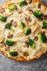 Closeup of fresh pizza with broccoli, chicken and cheese on the wooden board on the table. Vertical top view from above