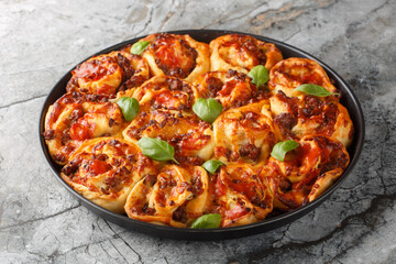 Rustic Pizza rolls filled with italian sausages, Mozzarella, tomato and basil closeup on the bakong dish on the table. Horizontal