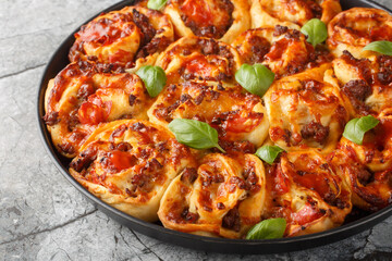Homemade Pizza swirl Rolls with italian sausages, Mozzarella and basil closeup on the bakong dish on the table. Horizontal