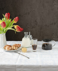 Coffee, milk and a cake with pink tulips on the table