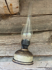 A kerosene lamp hangs on the wall of an old log shed.