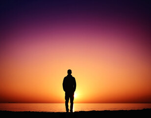 Fototapeta premium silhouette of a person on the beach at sunset. peaceful and contemplative mood in solitude.