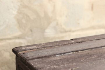 Wooden plank table with blurred concrete wall background, selective focus. Empty old table and wall for product display or installation
