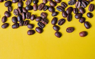 Roasted coffee beans on yellow background with copy space. Coffee grains on yellow background