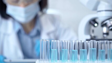 Test tubes with a blurred scientist in a lab coat in the background