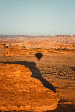 Ballonfahrt Flug &uuml;ber die W&uuml;stenlandschaft mit dem Schatten des Ballons auf dem Sand von AlUla in Saudi-Arabien mit Blick auf Felsformationen