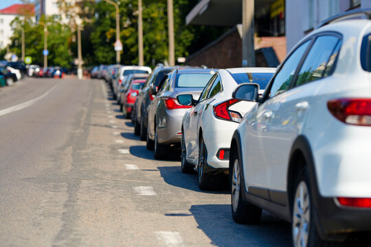 Cars parked tight along the roadside, crowded parking lot. Cars parked in row along roadside at downtown, parking problems not enough free space..