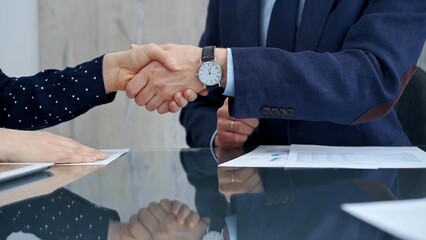 Professional handshake between two professionals and applauds at a corporate meeting with reflection on table over a business meeting. Business people concept