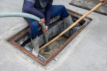 A man is carrying a suction hose from the Waste Water Treatment Plant to the suction truck.