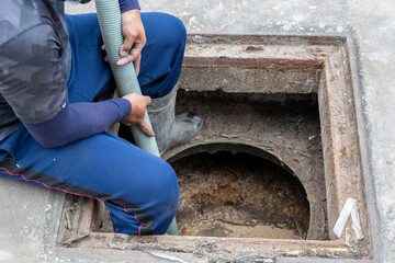 A man is carrying a suction hose from the Waste Water Treatment Plant to the suction truck.