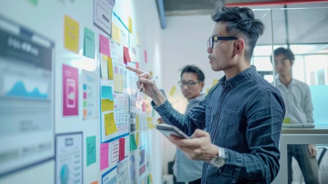 Asian UX Developer and UI Designer Presenting Mobile App Interface Design on Whiteboard in Modern Office Meeting. Creative Digital Mobile App Development Agency. Digital Transformation.