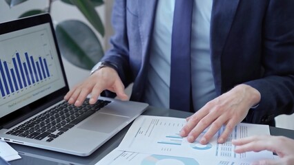 Fototapeta premium Professional businessman gestures to charts on laptop screen during corporate meeting. Business concept