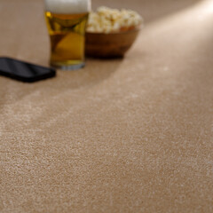 Relaxing Evening Setup with Beer, Popcorn, and Smartphone on Soft Beige Carpet