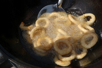 Calamari rings in deep frying in pan. Close up of frying onion rings in the fryer in hot oil.