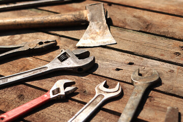 Old hand tool on a wooden surface. Adjustable wrench, wrench, ax and pliers. Tools for repair and construction, selective focus