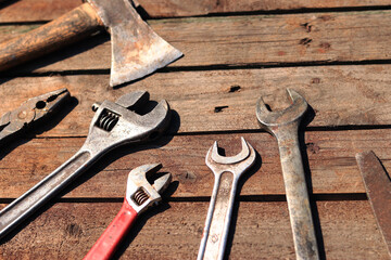 Old hand tool on a wooden surface. Adjustable wrench, wrench, ax and pliers. Tools for repair and construction, selective focus