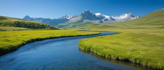 Obraz premium A river runs through a verdant valley, adjacent to a lavish green field Behind, towering mountain ranges stand tall