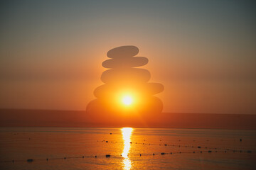 Pyramid of stones against the background of sunset or sunrise on the sea, artistic creative technique in photography multiple exposure, double exposure