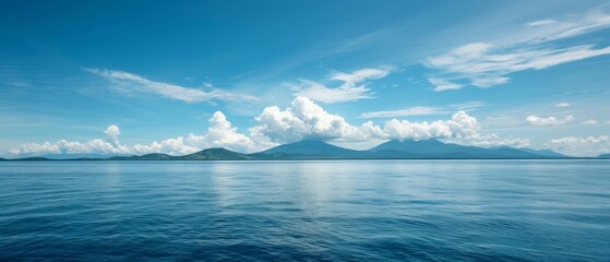 Fototapeta premium A vast expanse of water, surrounded by mountains in the distance, and cloud-dotted skies above