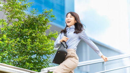 夏の屋外を元気よく歩く日本人ビジネスウーマン