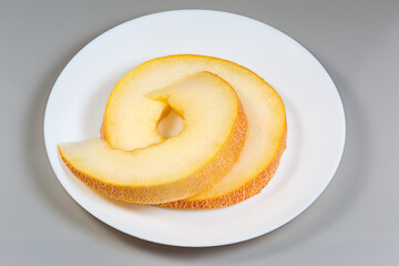 Pieces of the yellow melon cut across on white dish