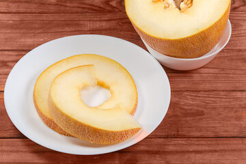 Pieces of melon cut across against the melon half with seeds