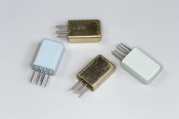 Сompact electromechanical relays in metal sealed casings on gray background