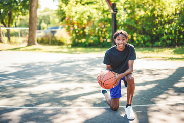 portrait of a teen playing with a basketball in park