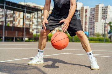 A basketball player in mid-dribble, focused on controlling the ball during an outdoor game on a city court.