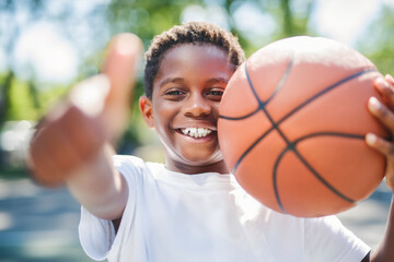 portrait of a boy kid playing with a basketball in park