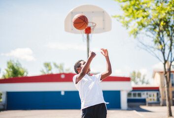 portrait of a boy kid playing with a basketball in park