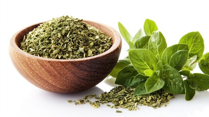 A close-up shot of dried oregano flakes in a wooden bowl, with fresh oregano leaves artistically scattered beside it, isolated on white.