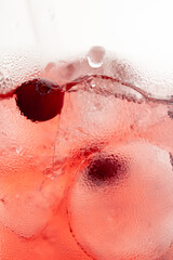 Fototapeta premium macro frame of glasses with cool red cocktail ice cubes condensation and drops on the glass fruity red balls