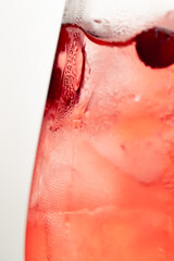 macro frame of glasses with cool red cocktail ice cubes condensation and drops on the glass fruity red balls