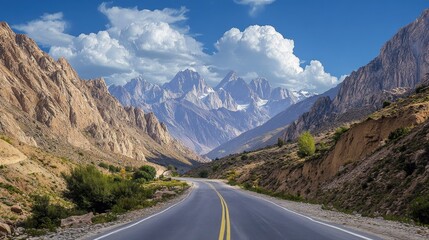 Fototapeta premium A scenic route through a mountainous area, with towering peaks and a clear blue sky in the background.